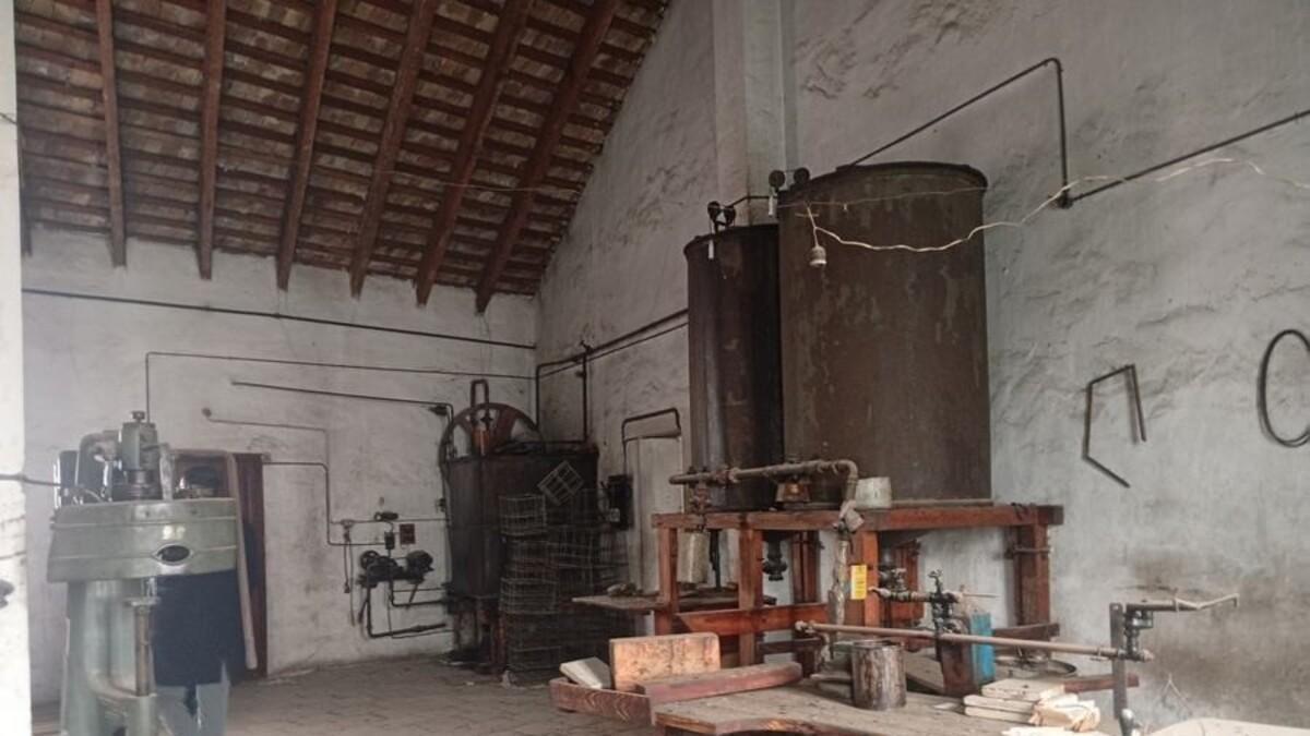 Sala de máquinas, con depósitos cilíndricos y bancada de trabajo con prensas y grifos