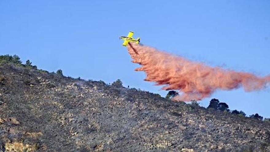 Una avioneta arroja un líquido retardante sobre la zona afectada por el incendio de Gilet.