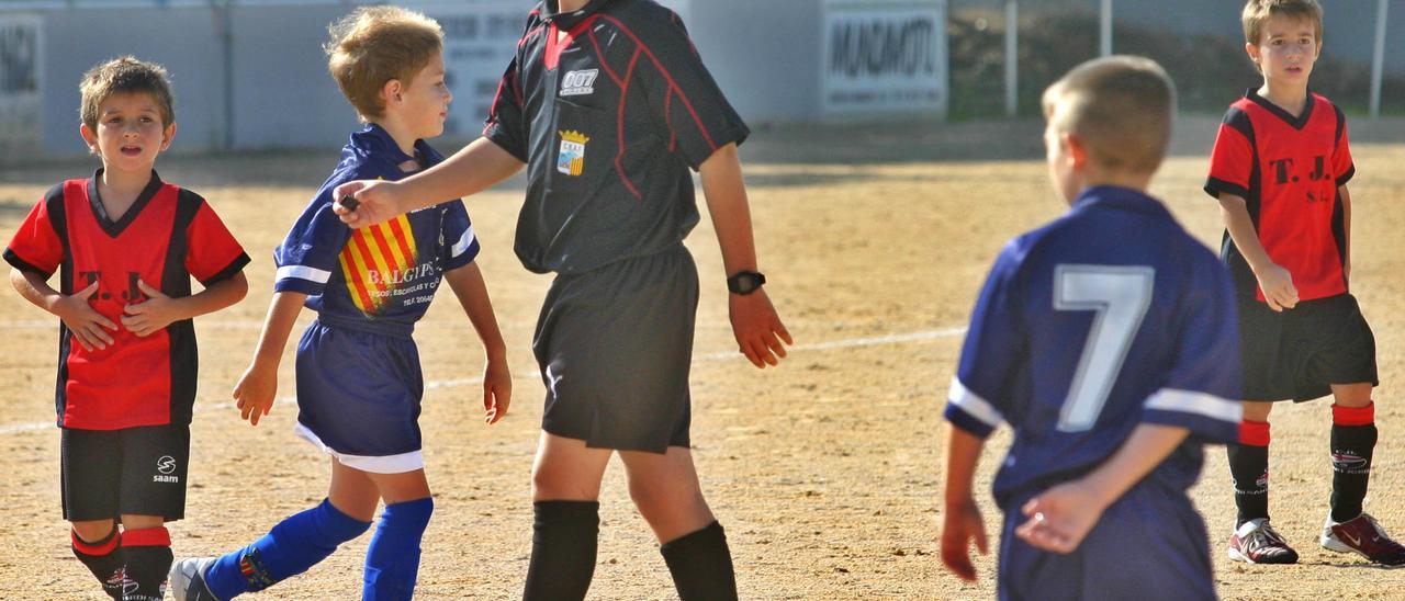 Un árbitro dirige un partido de fútbol base.