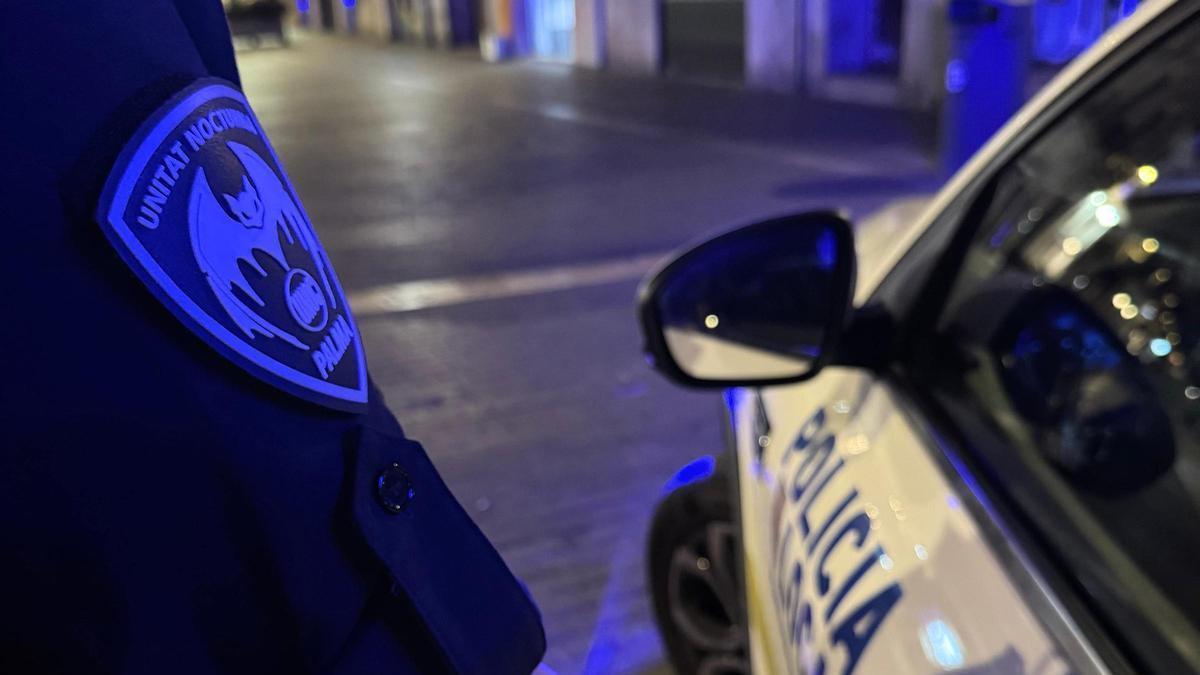 Un agente de la Unidad Nocturna de la Policía Local de Palma, junto a su coche patrulla