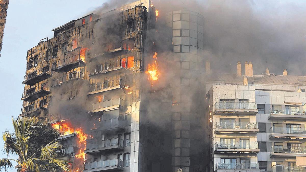 El fuego devora uno de los dos edificios de la avenida Maestro Rodrigo, mientras el viento dobla las ramas de una palmera.