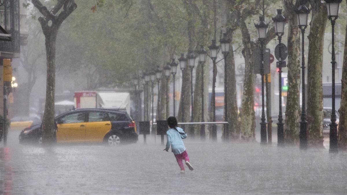 Una niña juega en la calle durante una tormenta en Barcelona.