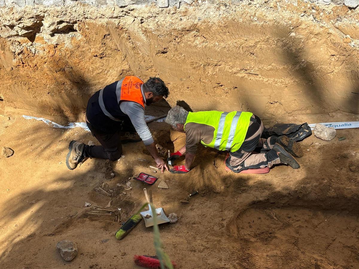 Un arqueólogo y un peón trabajan para sacar a la luz uno de los esqueletos del cementerio islámico.
