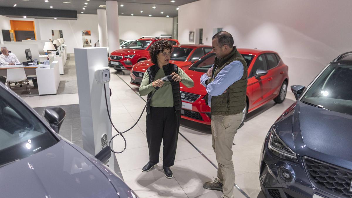 Un hombre conversa con una comercial para comprar un coche en un concesionario de València.