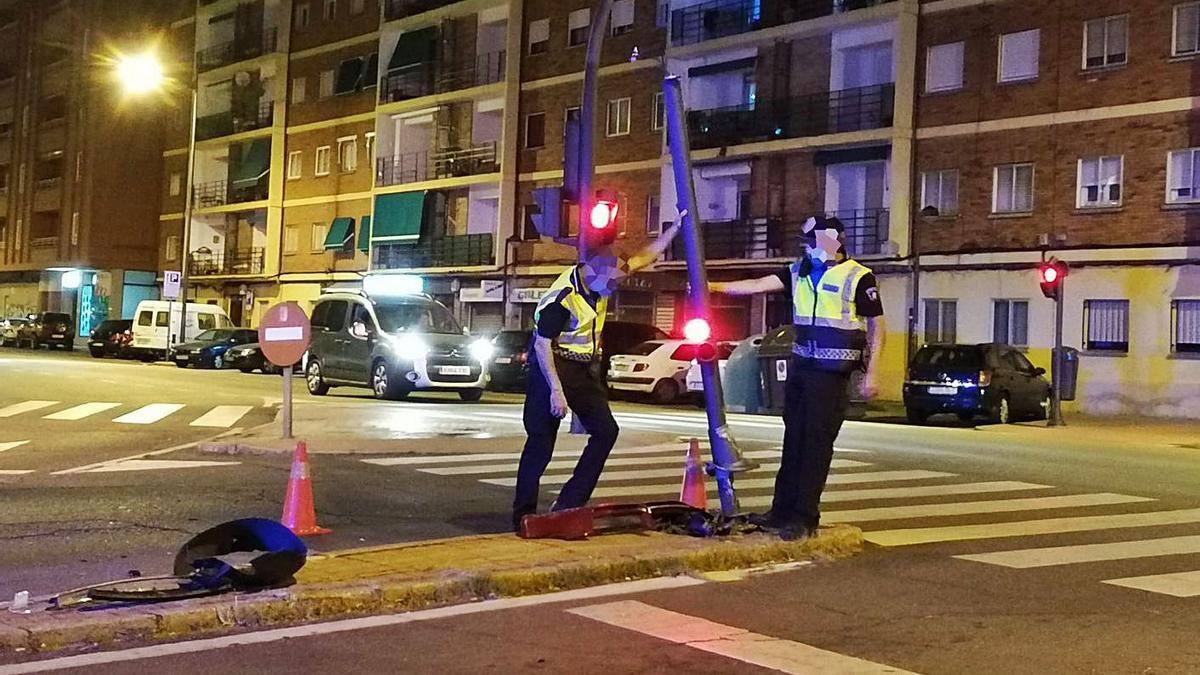 Dos agentes de la Policía Municipal levantan el semáforo derribado por un Audi.