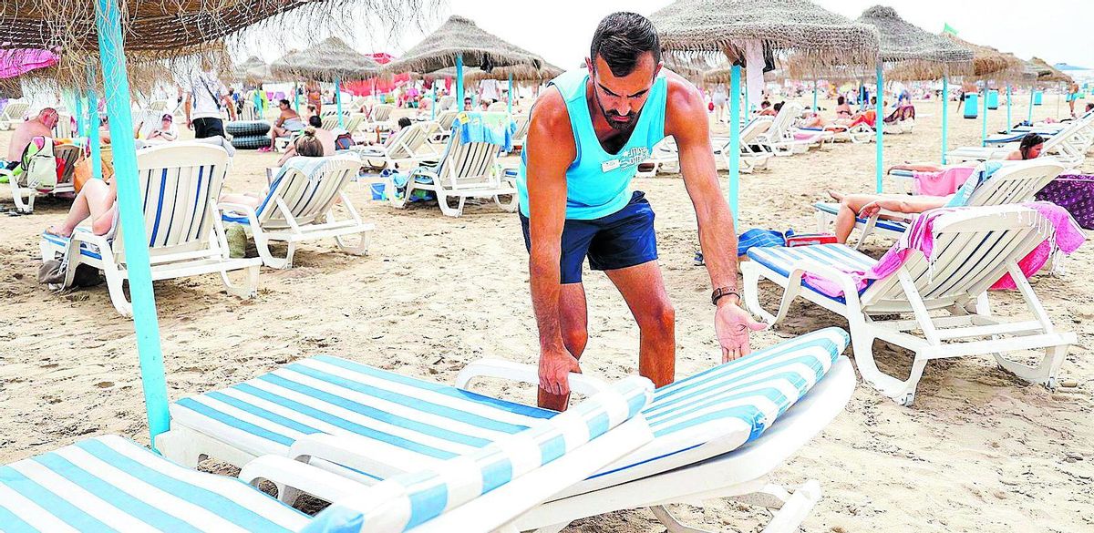 Un trabajador coloca las hamacas para alquilar en una playa.