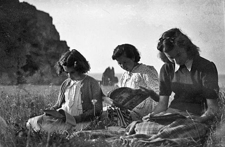 Tres jóvenes leyendo en la costa luarquesa en una fecha por determinar. | MUSÉU DEL PUEBLU D’ASTURIES.