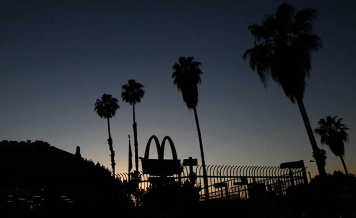 La posta de sol silueteja els arcs del logo d’una cadena de menjar ràpid a Los Angeles (Estats Units).