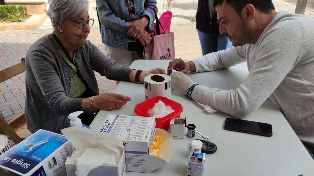 Un voluntario realizando la prueba diabetológica a una mujer.