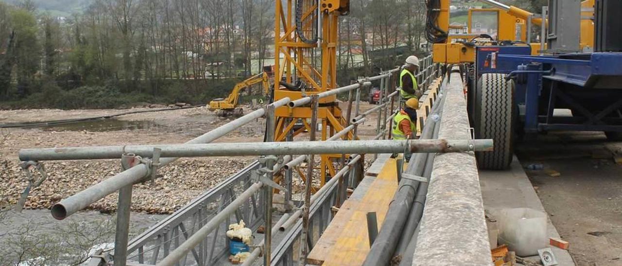 Trabajadores en la plataforma del puente sobre el Narcea; al fondo, tras los árboles, Cornellana.