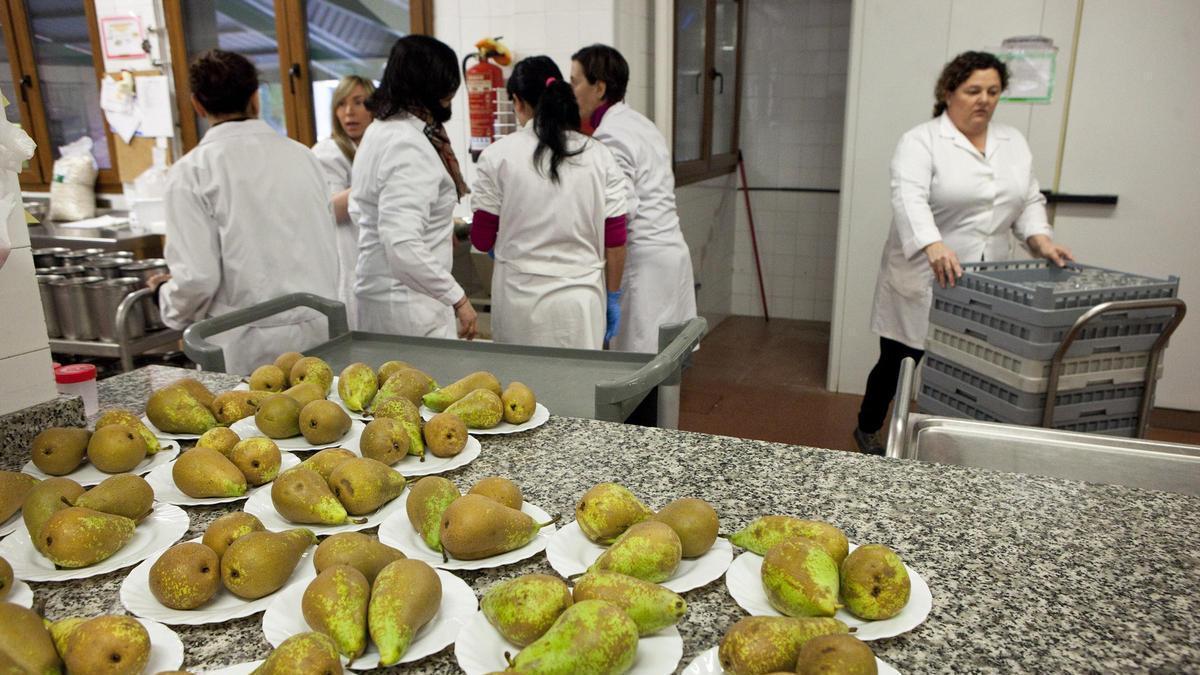 Un grupo de operarias preparan las mesas de un comedor escolar.