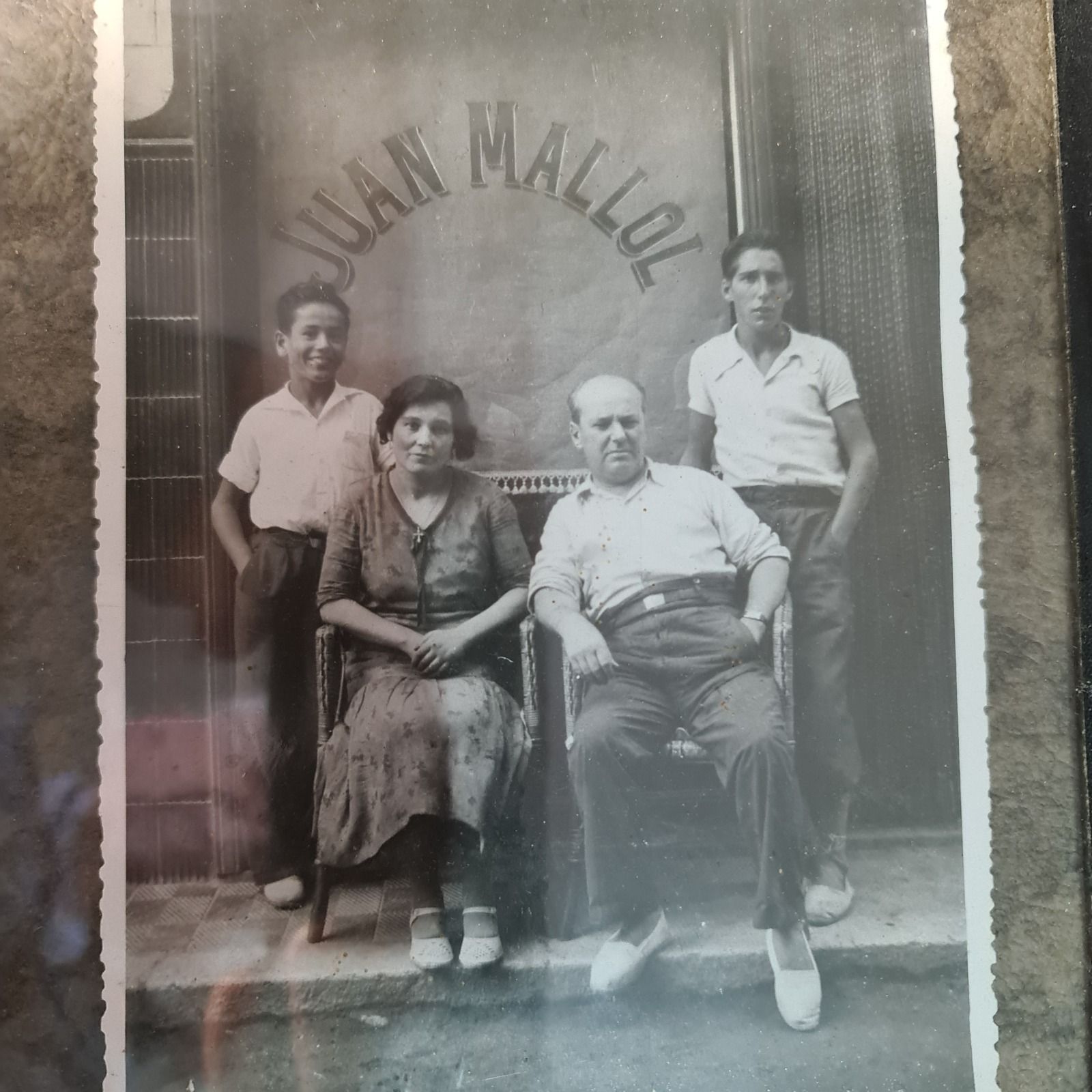 Joan Mallol nen, a l'esquerra, somrient, amb el germà i els pares, a la botiga vella