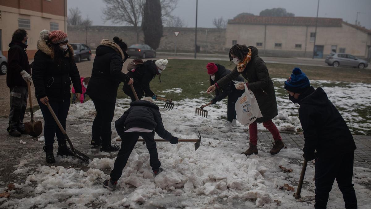 Una madre echa sal sobre la nieve helada en la entrada del Alejandro Casona.