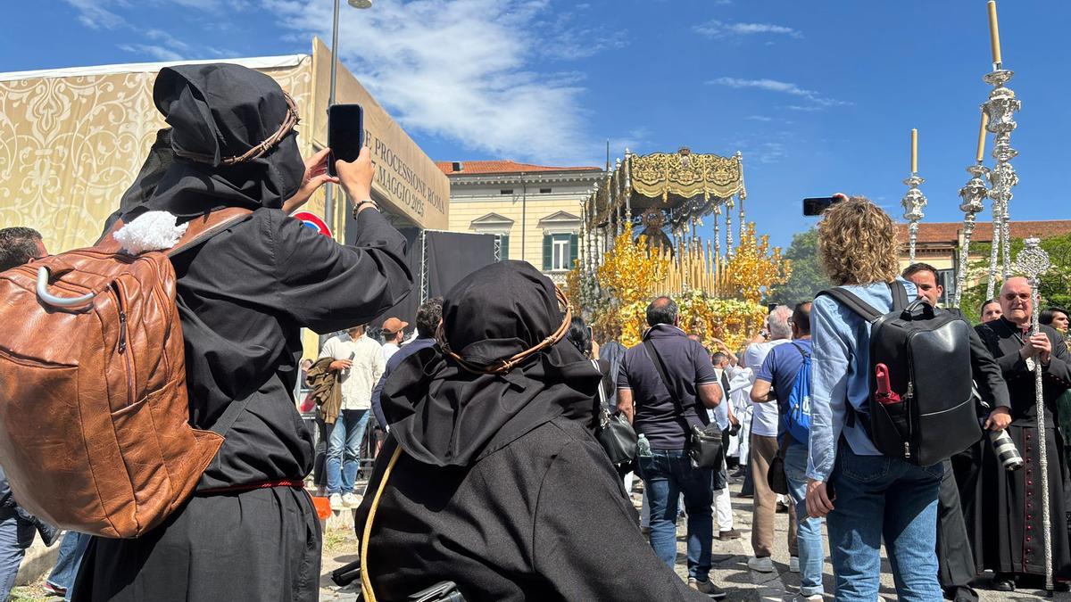 Dos cofrades de Sicilia asisten a la salida de la Virgen de la Esperanza por las calles de Roma.
