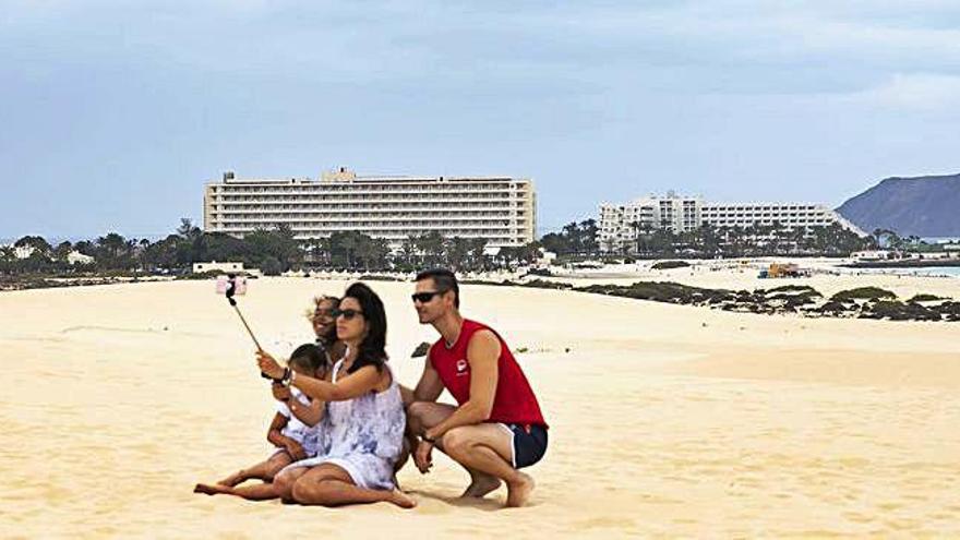 Una familia se fotografía con el hotel RIU Oliva Beach al fondo.