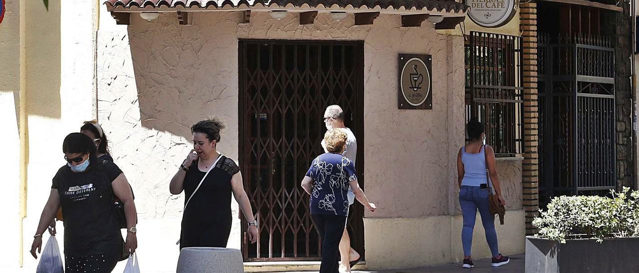 Varias peronas pasean frente a una cafetería de Alzira cerrada, en una imagen de archivo. | VICENT M. PSATOR