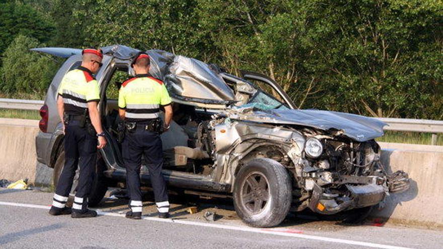 Dos Mossos observen el vehicle accidentat.