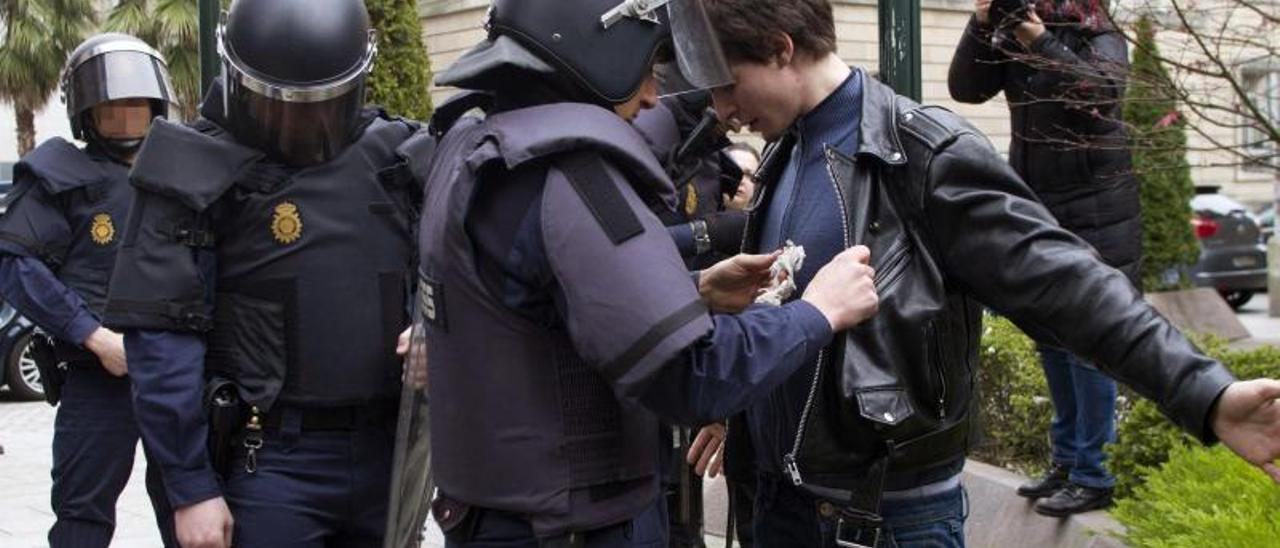 Un agente policial cachea a un joven durante una protesta en Vigo. |   // S. SAS/EFE