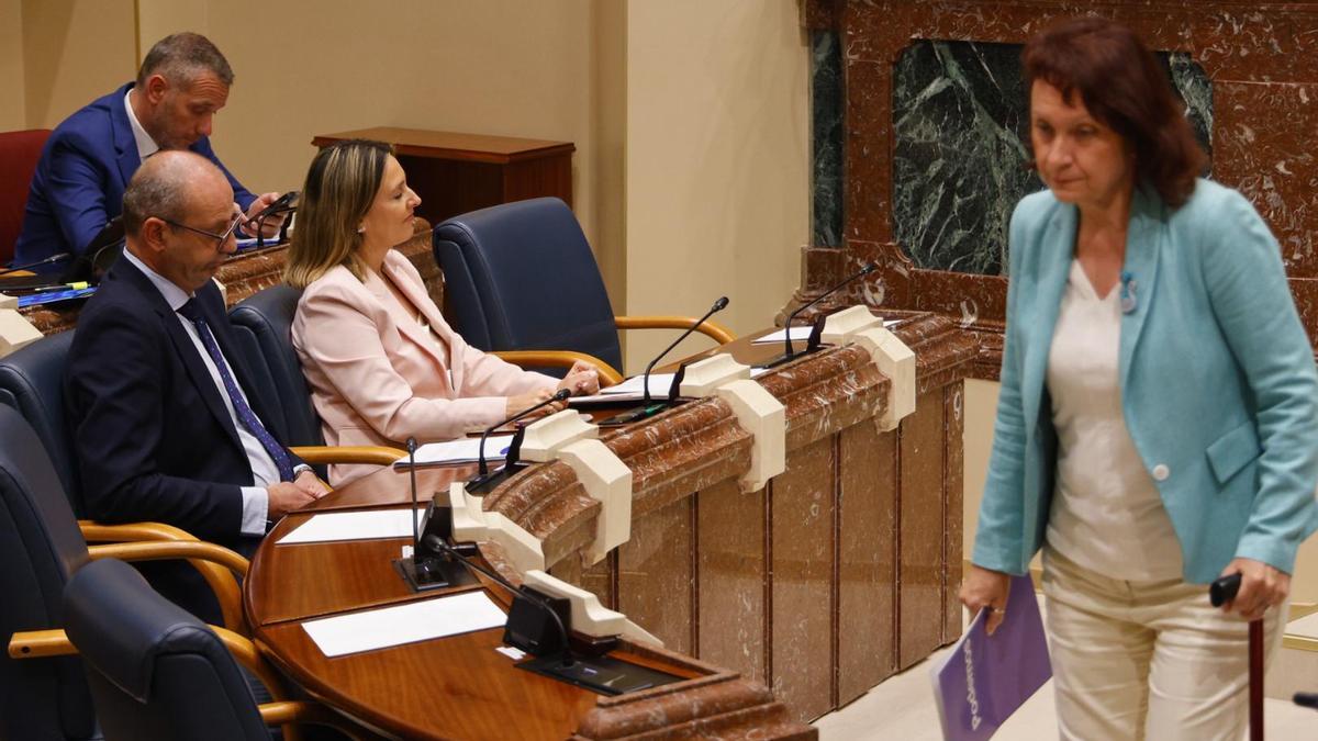 La diputada de Podemos, María Marín, se dirige a su asiento tras pasar ante los consejeros Conchita Ruiz y Víctor Marín.