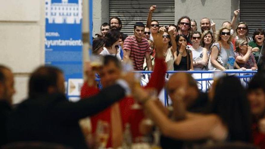 Varios de los invitados al pleno brindan en un bar en la plaza cerrada con vallas para el resto de los ciudadanos