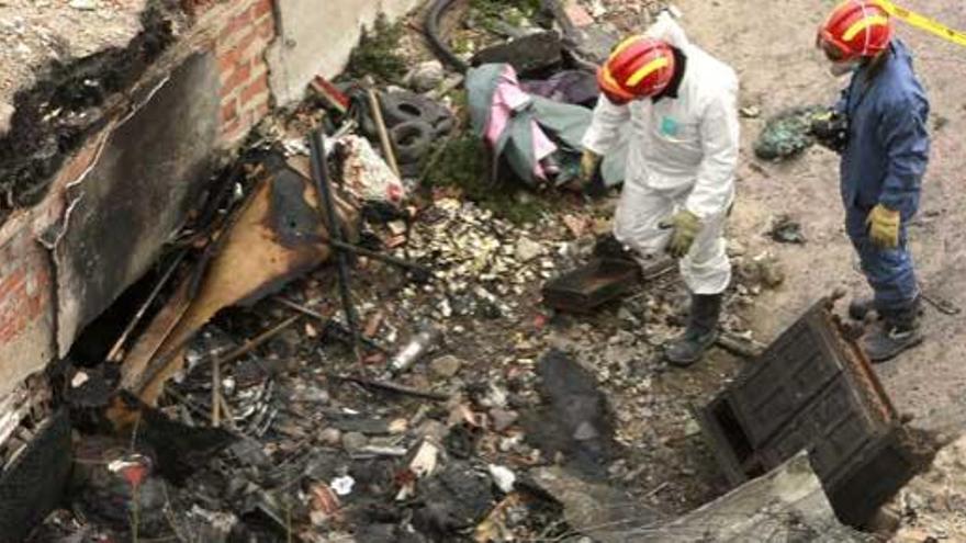 Dos técnicos observan los restos del incendio en el que han muerto cuatro personas.