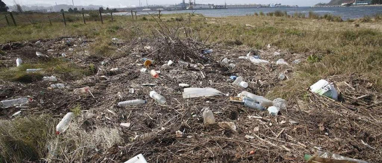 Basura arrastrada por la ría y acumulada en la playa de Zeluán, en primer término, con el estuario al fondo.