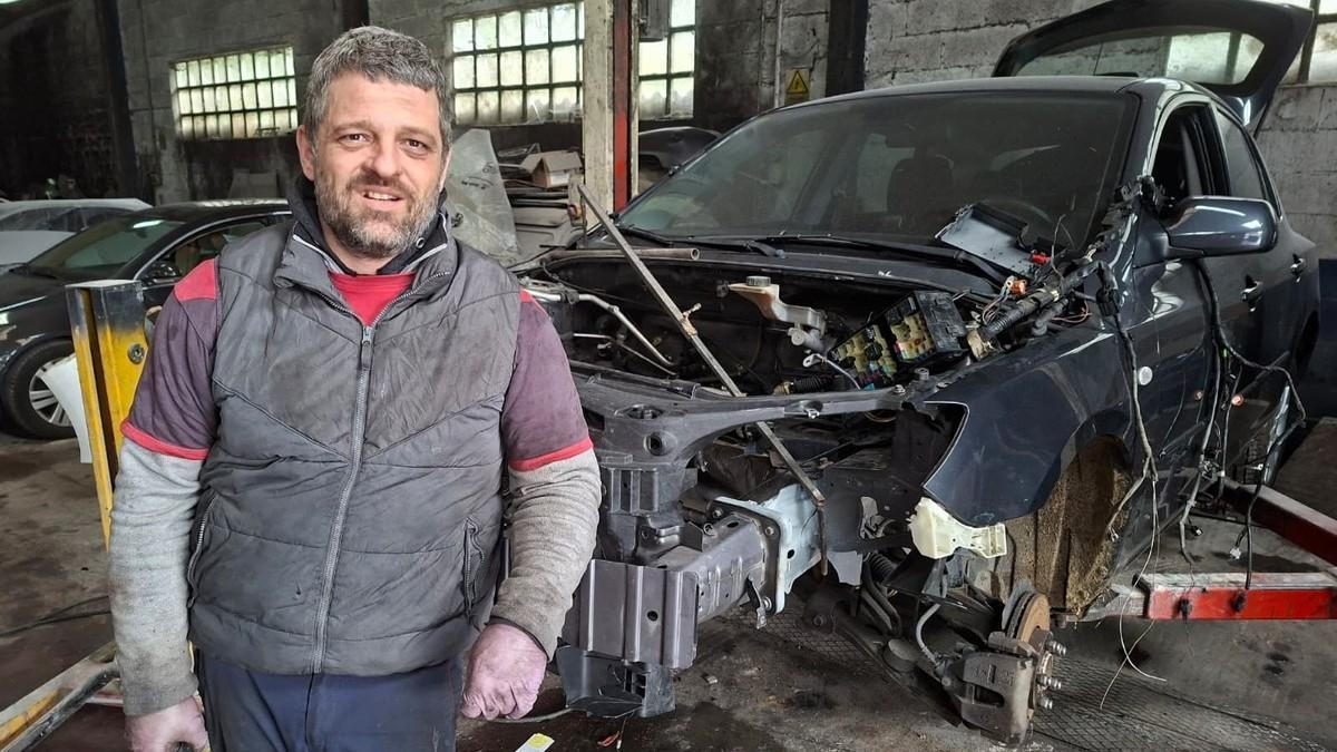 Uno de los trabajadores del taller mecánico Automóviles K7 junto a un vehículo en plena reparación