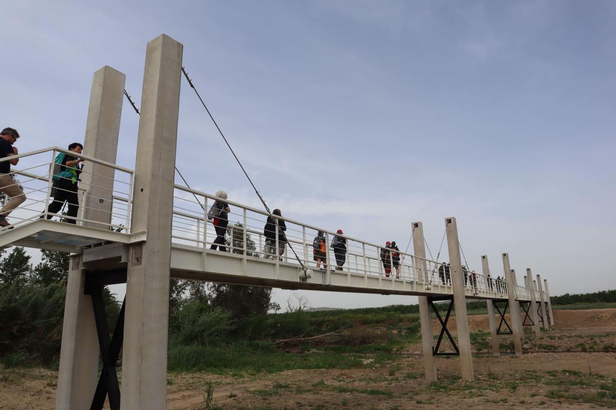 Personas cruzan la nueva pasarela sobre el río Búrdalo en Torrefresneda.