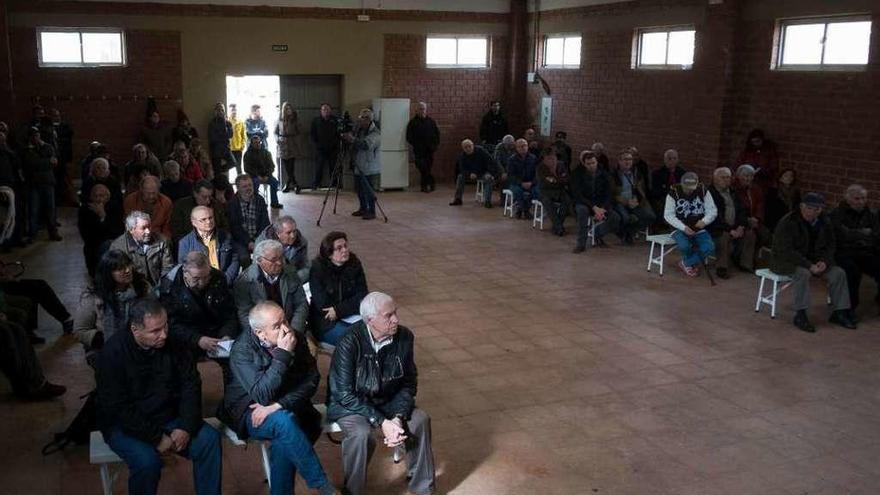 Asistentes a la asamblea informativa sobre la granja de porcino proyectada en Pozuelo de Tábara. A la derecha, promotor, alcalde, técnicos y representantes sindicales en la mesa.