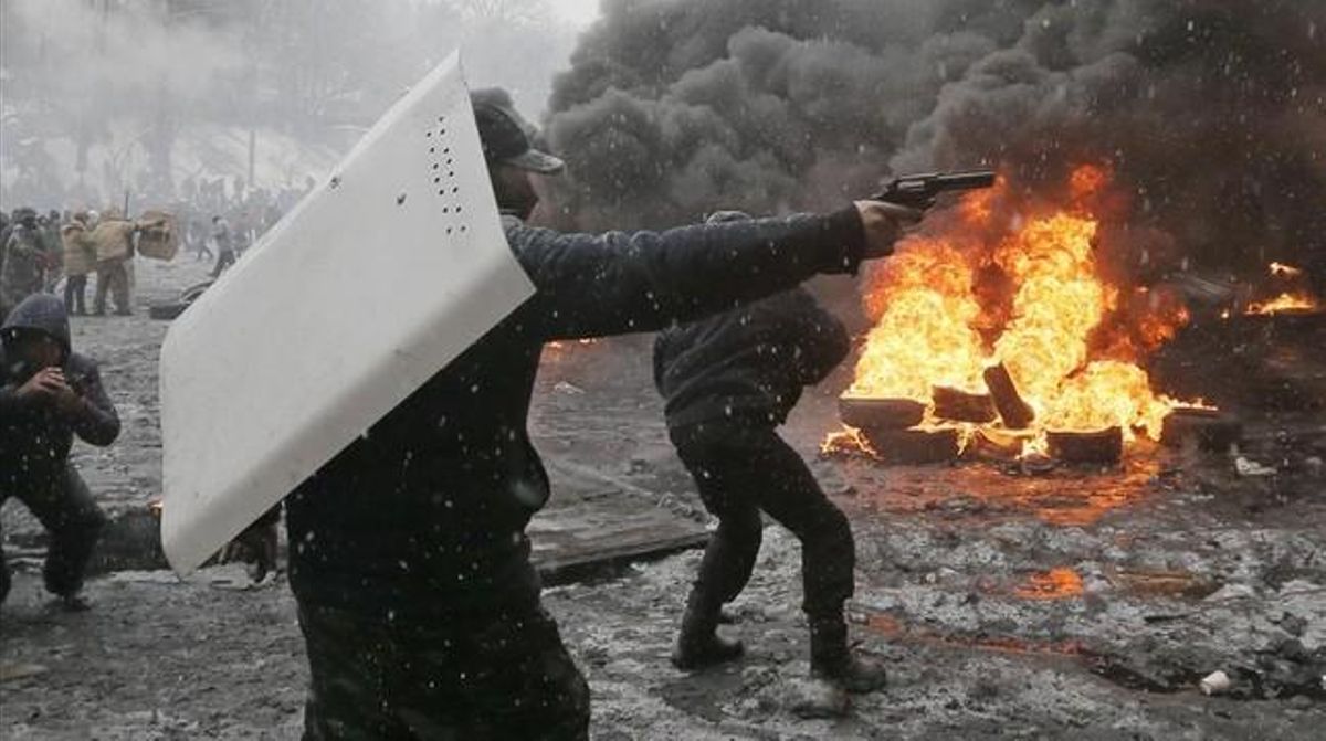 Un manifestant apunta amb una arma de foc durant un enfrontament amb la policia al centre de Kíev. Tres persones han mort en enfrontaments entre manifestants i la policia a la capital d’Ucraïna.