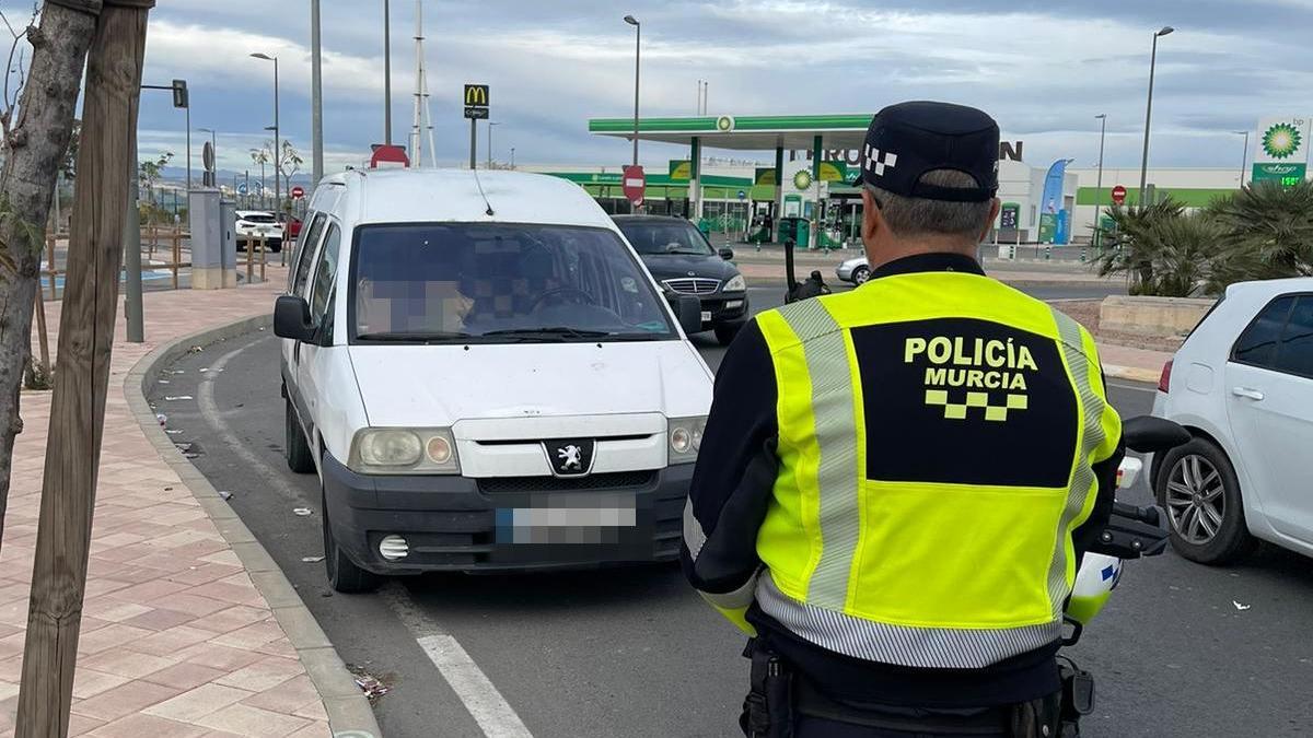 Un agente de la Policía Local de Murcia, junto al vehículo inmovilzado en el que viajaba el conductor.