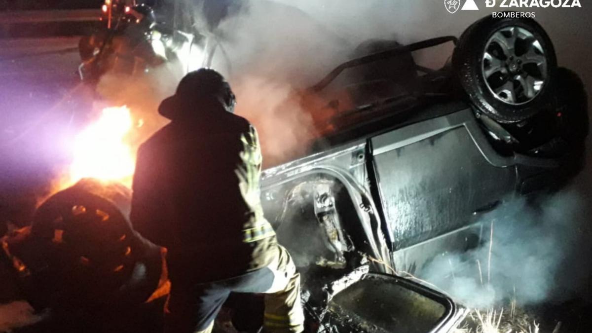 Un bombero trabaja en la extinción del fuego en los vehículos implicados en el accidente