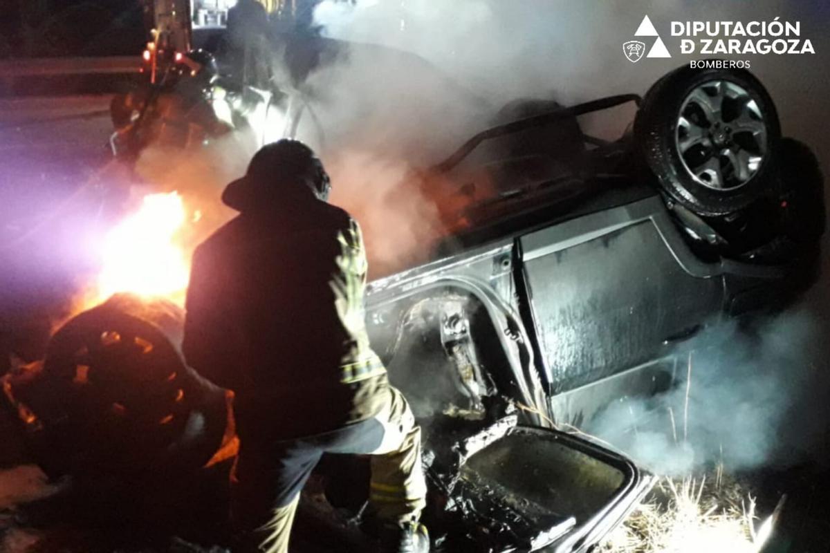 Un bombero trabaja en la extinción del fuego en los vehículos implicados en el accidente