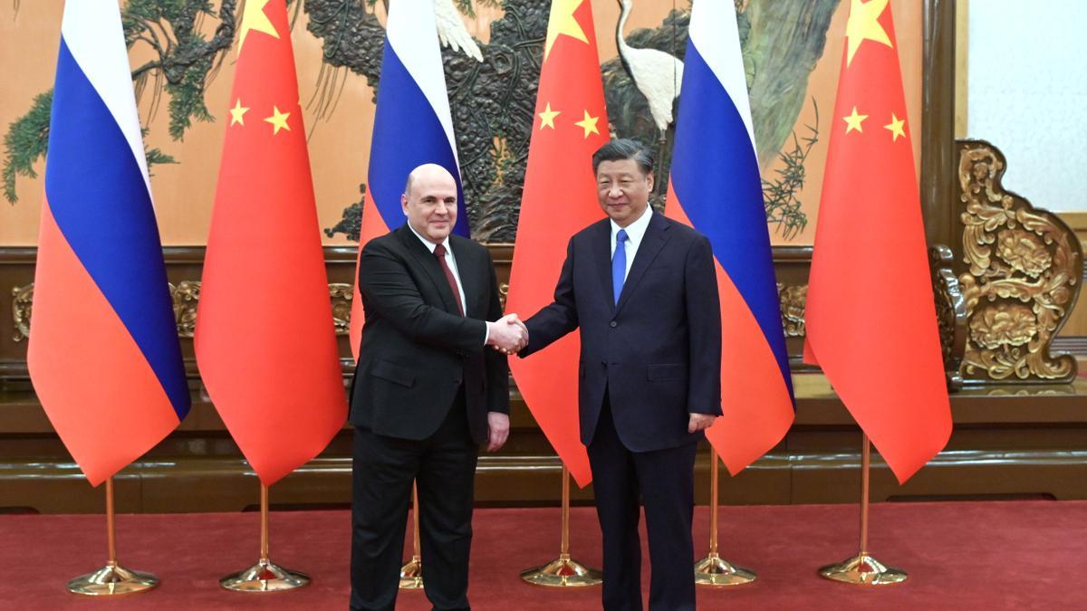 el primer ministro ruso, Mikhail Mishustin, da la mano al presidente chino Xi Jinping