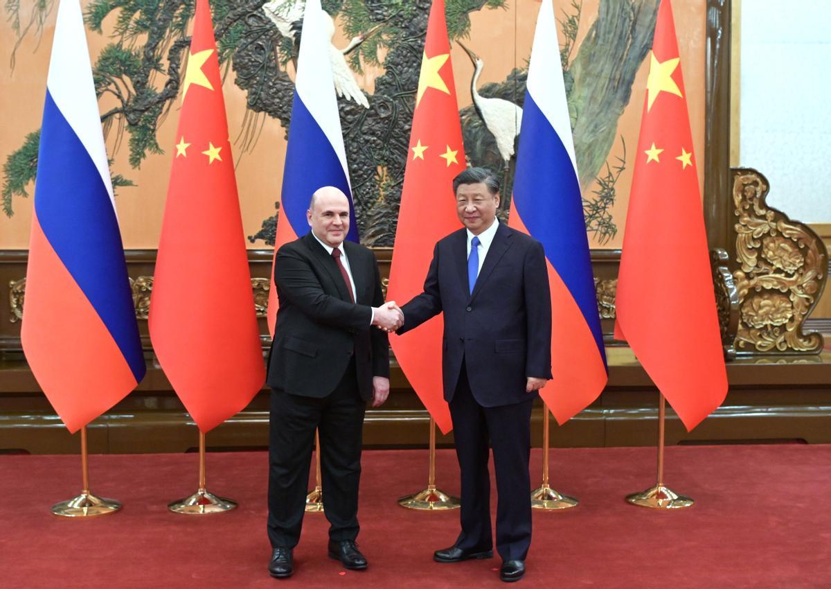 El primer ministro ruso, Mikhail Mishustin, da la mano al presidente chino Xi Jinping