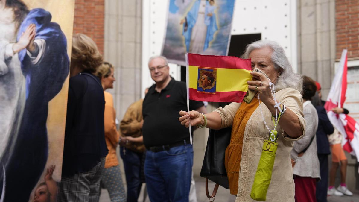 Una mujer muestra una bandera de España con la foto de Franco.