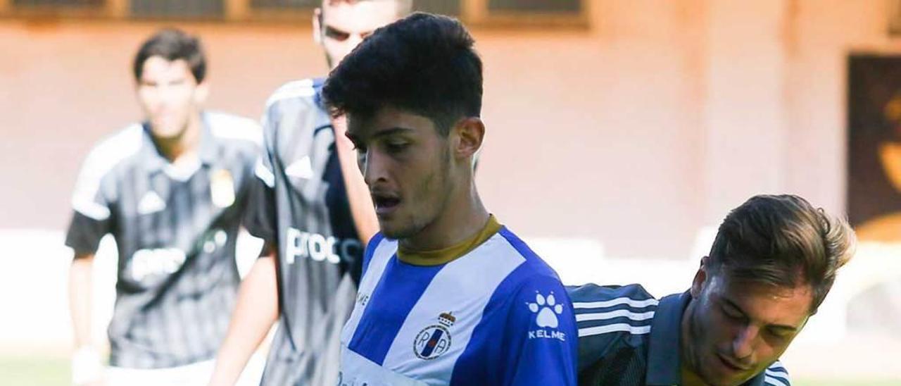 Sergio Ríos pelea un balón con Edu Cortina (Oviedo B).