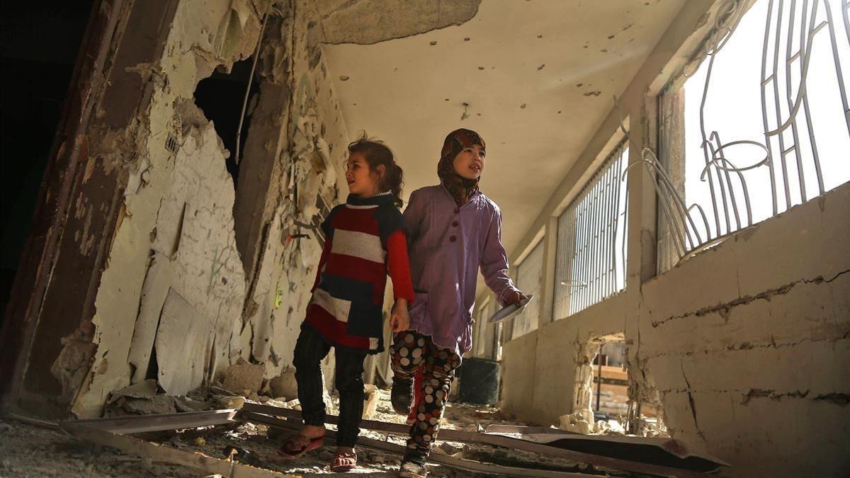 Dos niñas sirias recorren su escuela, destrozada el día anterior por los ataques áereos de la aviación gubernamental, en la sitiada ciudad de Saqba (Guta Oriental), el 9 de noviembre.