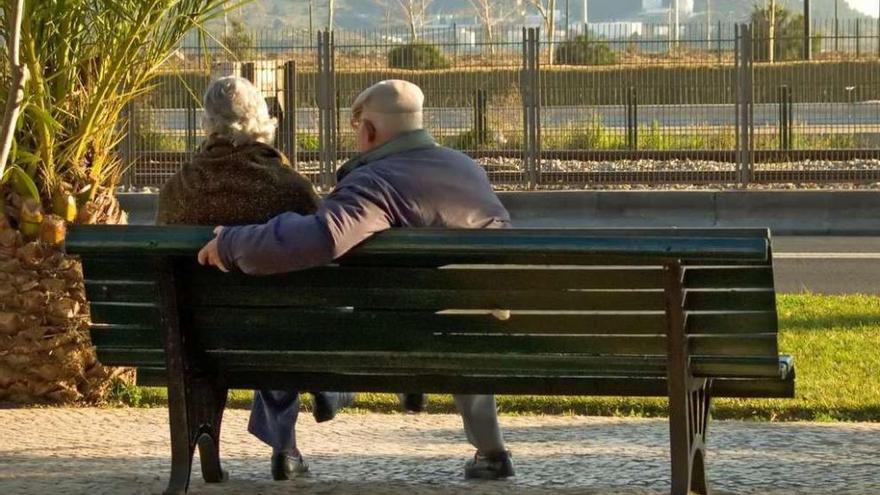 Una pareja de ancianos, sentados en un banco.