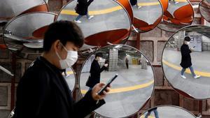 A man wearing a mask to prevent the coronavirus is reflected in the mirrors, in Seoul, South Korea, February 24, 2020.    REUTERS/Heo Ran