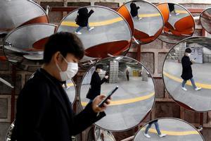A man wearing a mask to prevent the coronavirus is reflected in the mirrors, in Seoul, South Korea, February 24, 2020.    REUTERS/Heo Ran