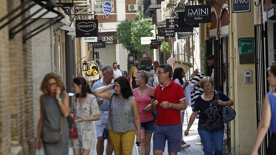 Transeúntes pasean por una concurrida calle comercial en Murcia.