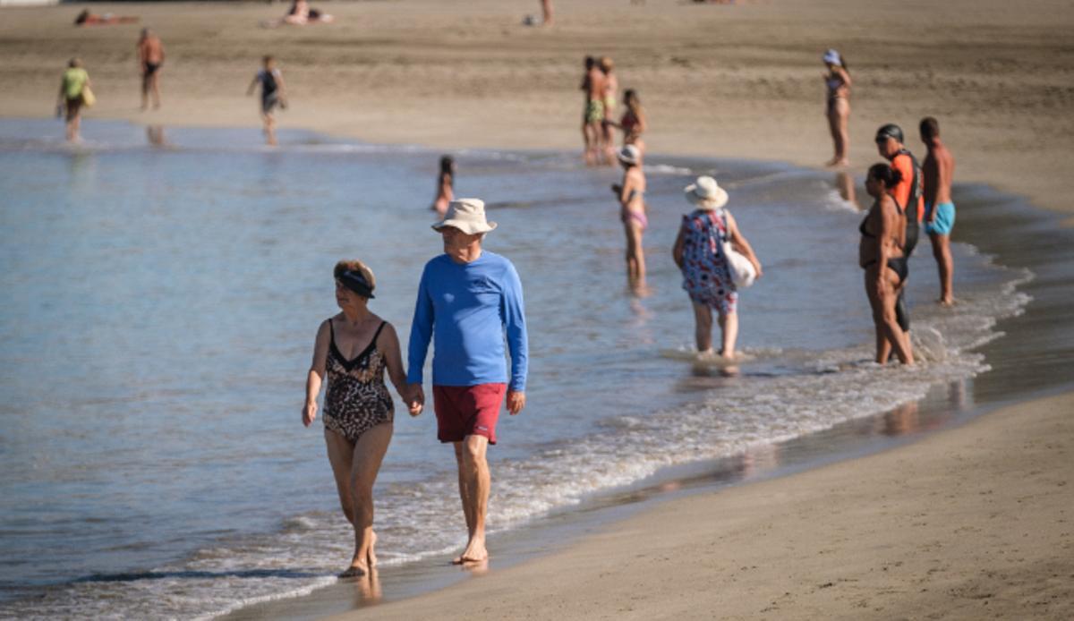Turistas pasean por la orilla de la playa de Los Cristianos, en el sur de Tenerife.