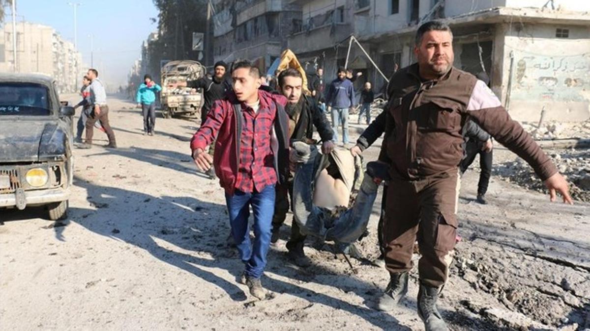 Varios sirios llevan el cuerpo de una víctima tras un bombardeo del régimen sirio en una área controlada por los rebeldes en Alepo, este lunes.