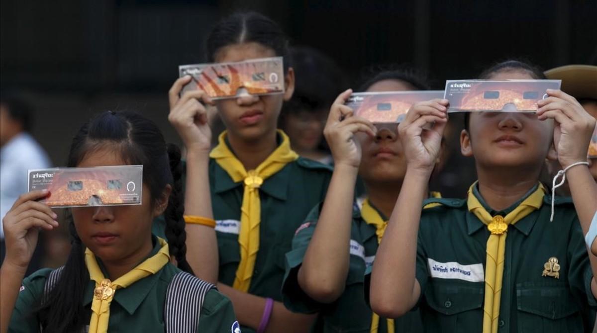 Estudiantes miran el eclipse a través de unas gafas especiales en Bangkok, Tailandia. 