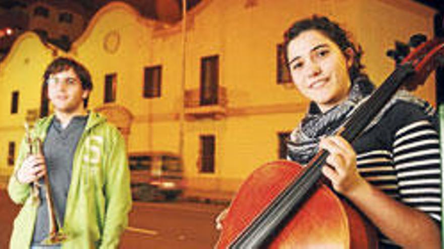 Darío Rodríguez y Paula Martos posan con sus instrumentos frente a Can Ventosa, tras un ensayo con la orquesta.