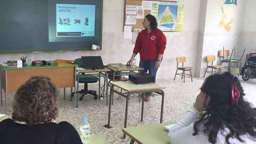 Desarrollo de una ponencia por parte de una responsable de Cruz Roja. A la derecha, asistentes a la exposición.