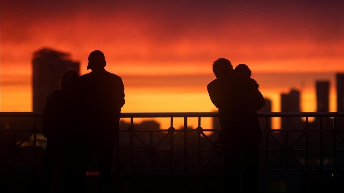 Varias personas contemplan la puesta de sol en Moscú desde un mirador