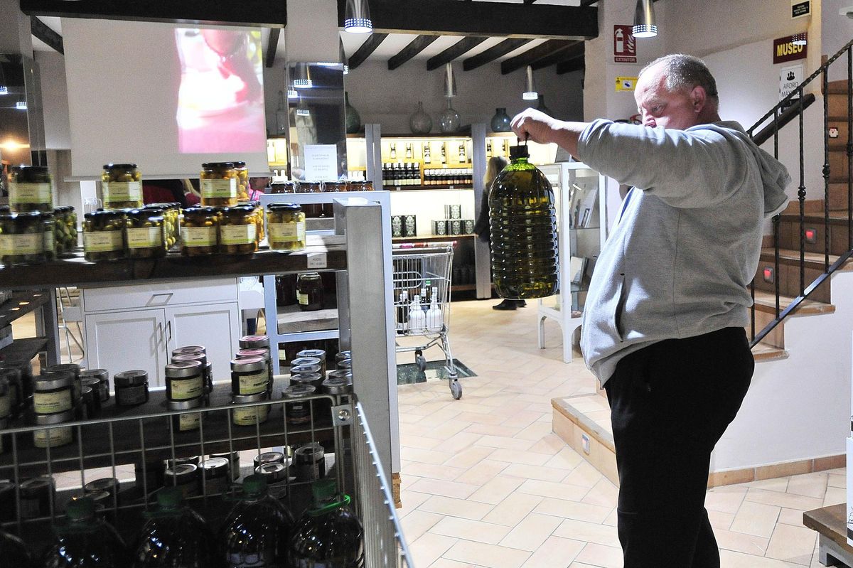 Un hmbre sostiene un garrafa de aceite en un almzara de Elche.