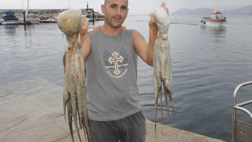 Un marinero de Bueu muestra dos pulpos en el primer día de la nueva campaña. // Santos Álvarez